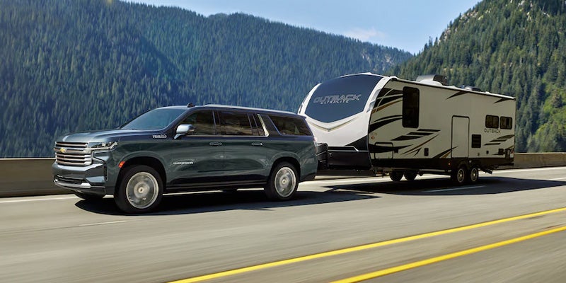 2022 Chevrolet Suburban driving on road towing camper trailer