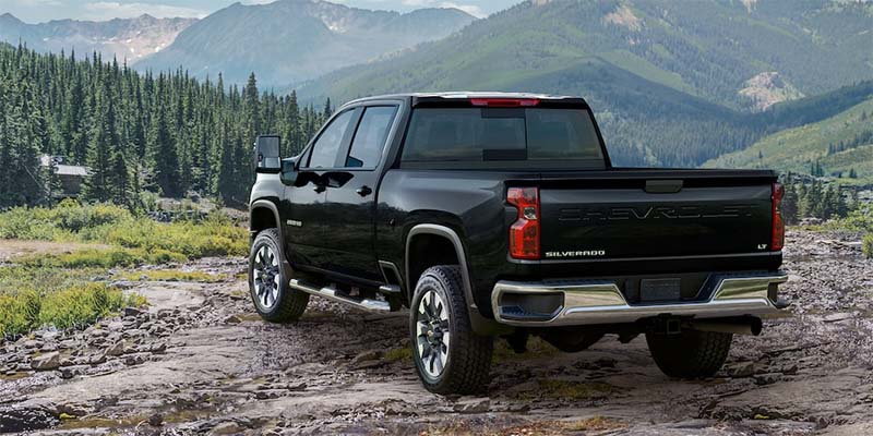 Rear angled view of a black 2023 Chevy Silverado HD parked facing mountains in the distance