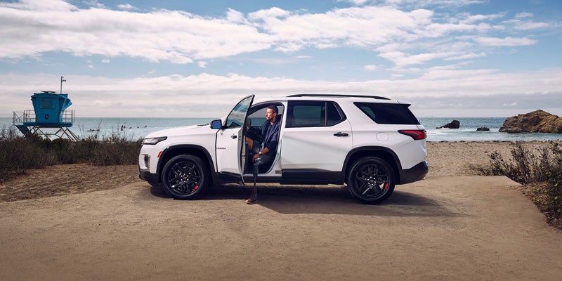 Man in drivers seat 2023 Chevrolet Traverse parked at the beach with his door open