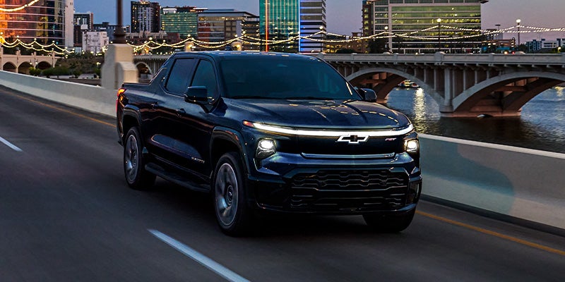 2024 Chevrolet Silverado EV driving over bridge with headlights on