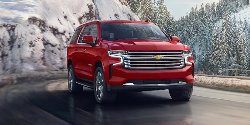 Red 2024 Chevrolet Suburban driving on road in snow