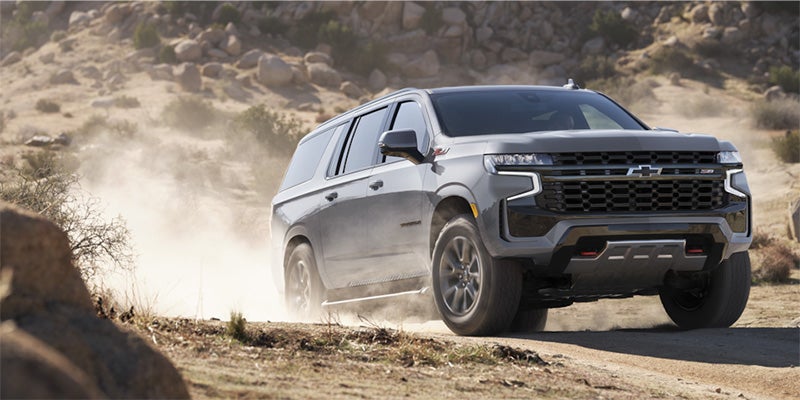 Gray 2024 Chevrolet Suburban driving on dusty road