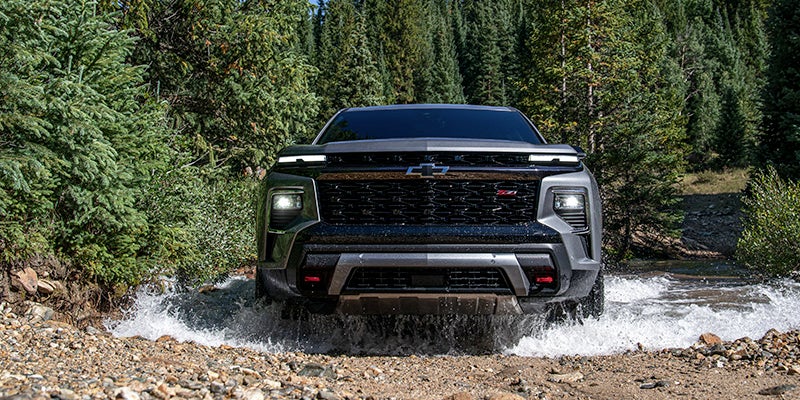 A 2024 Chevrolet Traverse driving through a large puddle on a rocky road