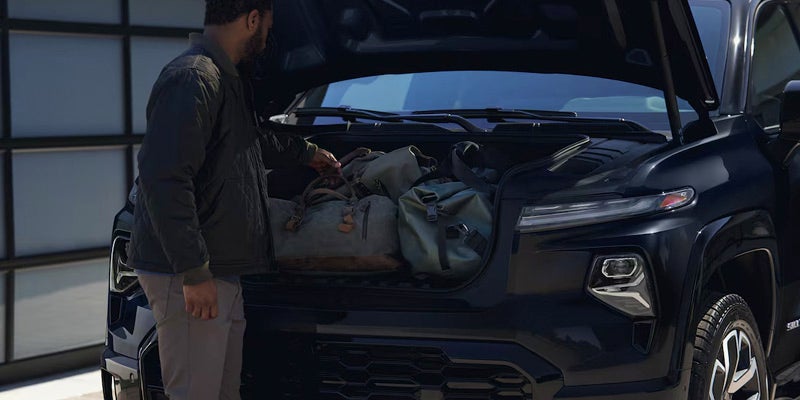 Man packing bags in the trunk of a 2024 Chevrolet Silverado EV