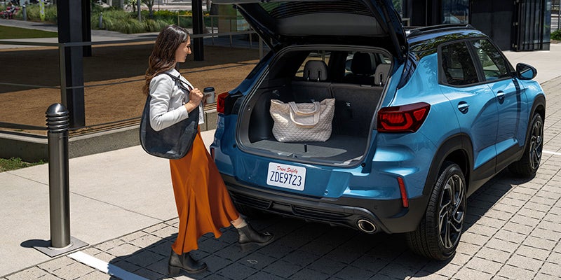 Woman standing at the back of a 2025 Chevrolet Trailblazer with trunk open and bag inside
