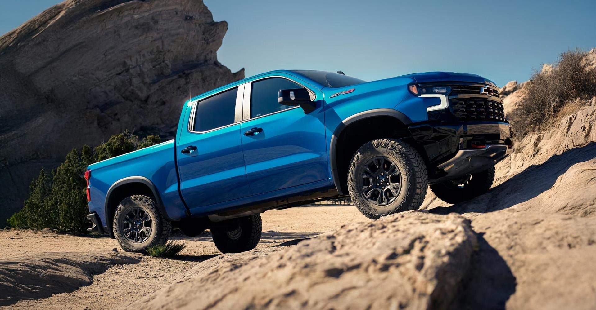 Blue Chevy Silverado 1500 climbing rocks